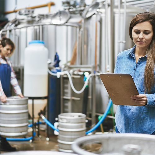 Brewing staff monitoring tanks and handling vessels as part of the beer filtration process.