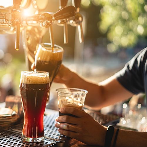 Beer being poured from a draft system in a brewery setting, representing beer filtration systems, sterile beer filtration, and cold filtered beer process used in industrial brewing.