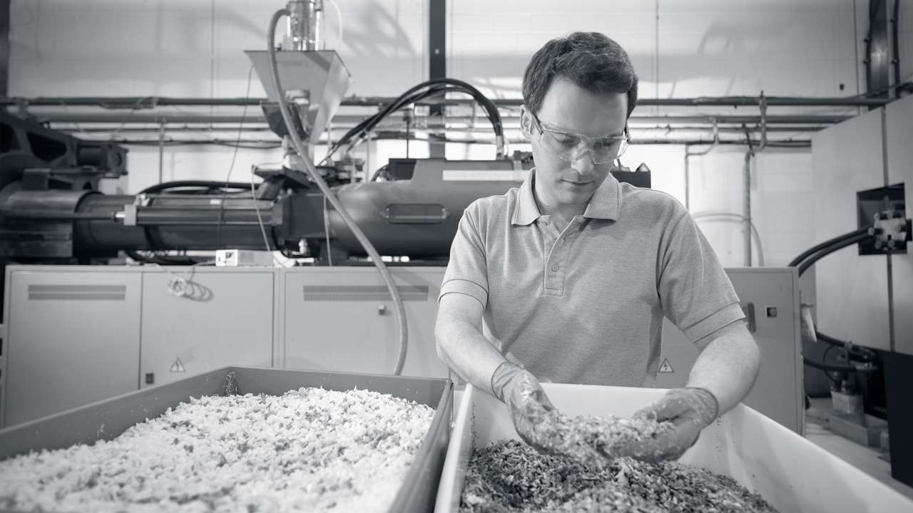 An employee checking the recycled plastic granuales