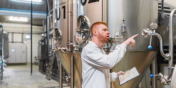Process operator inspecting stainless steel protein production tanks used in alternative protein downstream processing and filtration operation