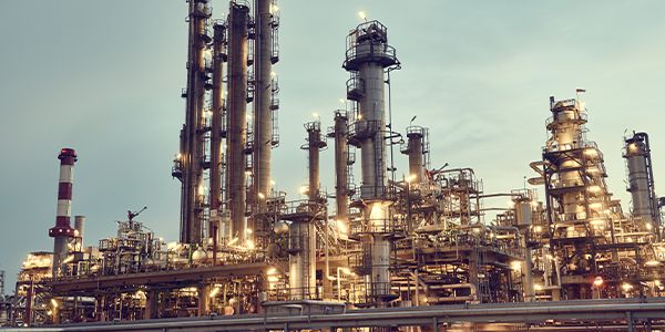 Industrial gas processing facility with tall distillation towers and illuminated piping against an overcast sky
